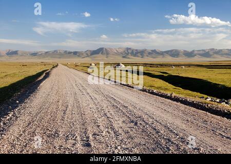 Unpaved road and yurts near Son-Kul lake and Tian Shan mountains in Kyrgyzstan Stock Photo