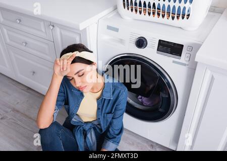 Young Woman Looking At Clean Clothes Out Of Washing Machine In Kitchen  Stock Photo - Alamy