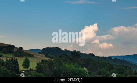 Cumulus congestus or towering cumulus - on the blue sky over hilly landscape Stock Photo