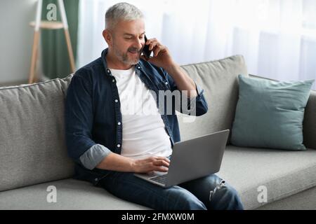 Matured man entrepreneur working online, using laptop and mobile phone Stock Photo