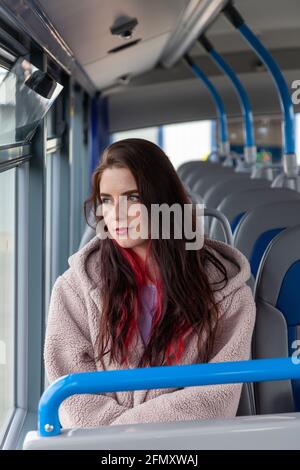A young woman rides a bus and stares serenely out the window Stock Photo