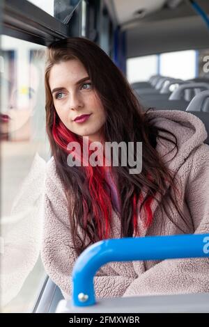 A young woman rides a bus and stares serenely out the window Stock Photo