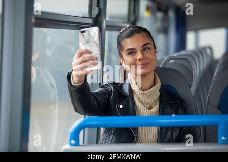 A woman taking a seflie of herself on a bus Stock Photo