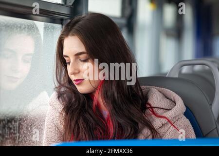 A beautiful young female student sitting on a bus with her eyes closed Stock Photo