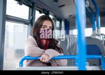 A young female student on a bus with her arms on a rail Stock Photo