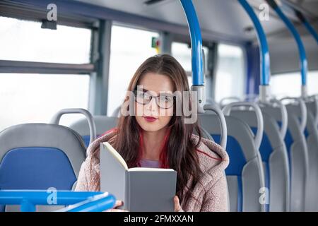 Woman reading book while traveling in bus Stock Photo
