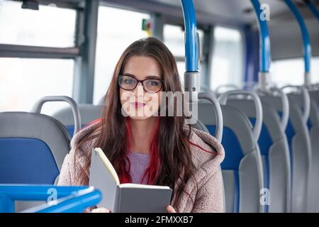 A beautiful woman in her 20's wearing glasses with a book in front of herself. Stock Photo