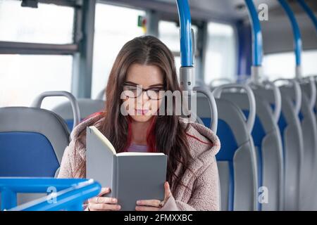 Woman reading book while traveling in bus Stock Photo