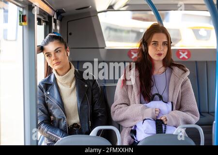 two women travelling on a bus together sitting side by side not talking. Stock Photo