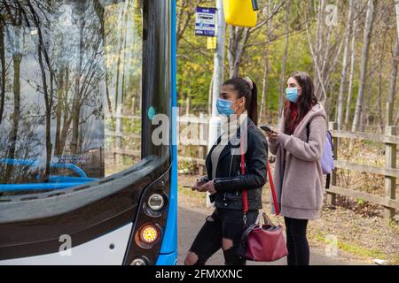 Two young women waiting at a bus stop in the street Stock Photo