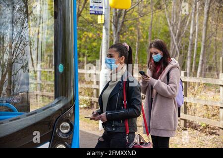 Two young women waiting at a bus stop in the street Stock Photo