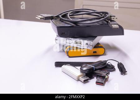 Hard discs and Pen drives also called flash drives used to store data from computer stacked together Stock Photo