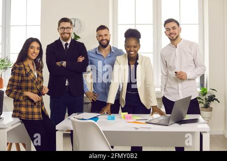 Team of happy young diverse business people standing in modern office and smiling Stock Photo