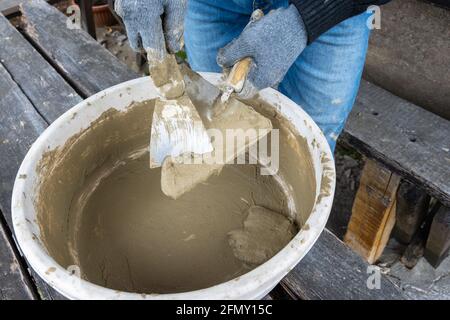 Masonry works. Working hands in blue gloves with a trowel. Stock Photo