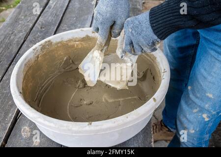 Masonry works. Working hands in blue gloves with a trowel. Stock Photo