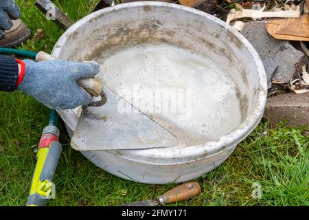 Hands cleaning trowels after finished masonry works Stock Photo