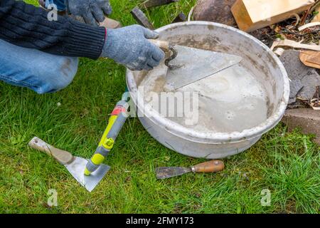 Hands cleaning trowels after finished masonry works Stock Photo