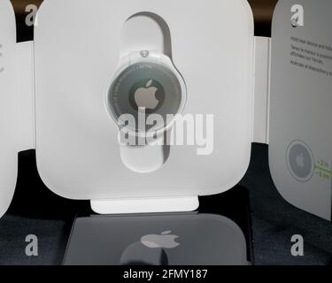 Morgantown, WV - 12 May 2021: Apple AirTag device in packaging reflecting the logo in back of Iphone mini Stock Photo