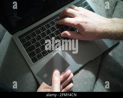 Shopping online. A man works on a laptop and pays with a credit card Stock Photo