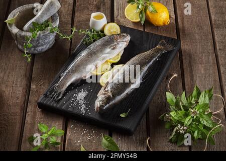 Two lemon stuffed raw trout and condiments on wooden background Stock Photo