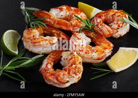 Grilled prawn tails with lemon and rosemary on black background Stock Photo