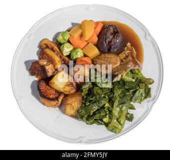 Roast lamb dinner with carrots, roast potatoes, brussel sprouts, roast onion, cabbage and gravy Stock Photo