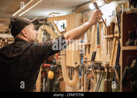 Male joiner chooses tools for work in workshop Stock Photo