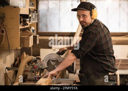 Close-up of young manual worker using circular saw Stock Photo