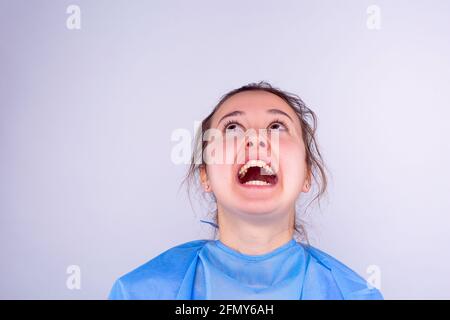 Portrait of a frustrated, upset, angry, screaming young woman doctor. Emotional doctor. Gray background with side space. Stock Photo