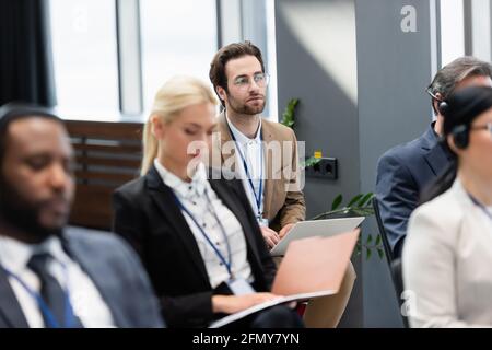 Businessman using laptop near interracial colleagues in conference room Stock Photo