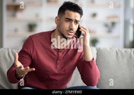 Closeup of sad arab guy having conversation on phone Stock Photo
