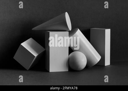 Abstract geometrical objects still life composition. Three-dimensional rectangular prism, cylinder pyramid cube, sphere on black gray background
