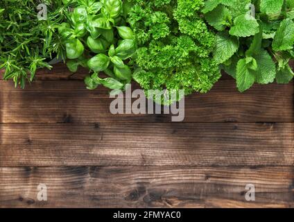 Fresh herbs on rustic wooden background. Basil, rosemary, parsley, mint. Top view Stock Photo