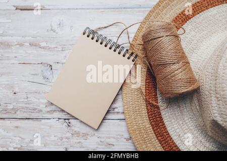 a skein of twine with a notepad for text and a hat on a wooden background. cutting and sewing concept. Stock Photo