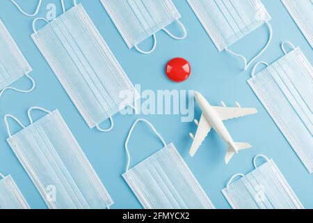 A toy white airplane and protective masks on a blue background with a red dot as the destination. The concept of a ban on flights and a mask mode, the Stock Photo