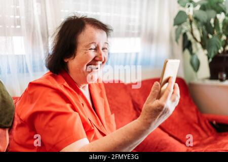 Elderly woman having a video call over the phone, laughing Stock Photo