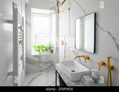 Modern luxury bathroom interior with white marble tiles and golden accessories  Stock Photo