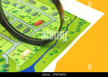 Choosing a building plot of land for house construction concept photo, magnifying glass and house on map Stock Photo