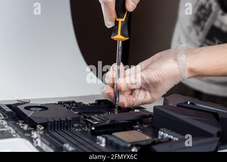 Technician is installing new fast high capacity SSD drive on the computer motherboard Stock Photo