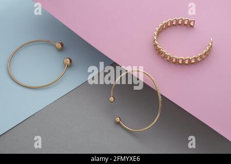 Three modern golden bracelets with diamonds on pastel color background with copy space Stock Photo