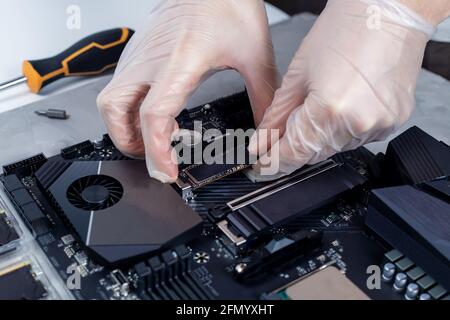Technician is installing new fast high capacity SSD drive on the computer motherboard Stock Photo