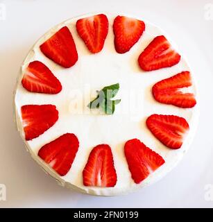 Top-down composition of homemade strawberry and cream cake with mint leaves on top. Stock Photo