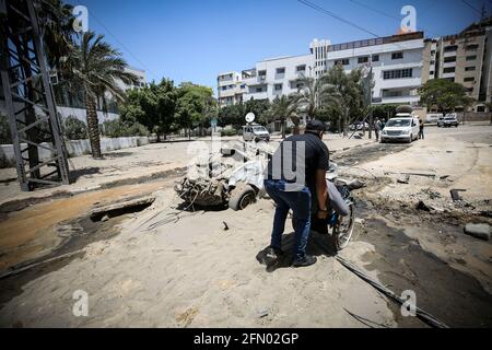 Gaza, Palestine. 12th May, 2021. People walk through the rubble of a building during the aftermath of overnight Israeli airstrikes on Gaza City. (Photo by Nidal Alwaheidi/SOPA Images/Sipa USA) Credit: Sipa USA/Alamy Live News Stock Photo