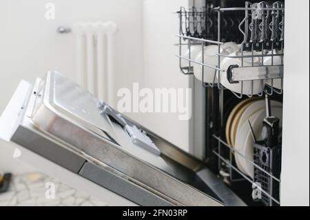 Open dishwasher with clean dishes in the white kitchen Stock Photo