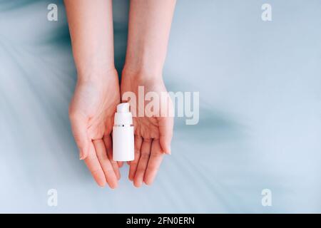 Hands holding skincare cosmetic lotion cream on blue background with palm shadows on it Stock Photo