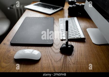 Photographer drawing and retouching image on laptop computer, using a digital tablet and stylus pen. Workspace at home  Stock Photo