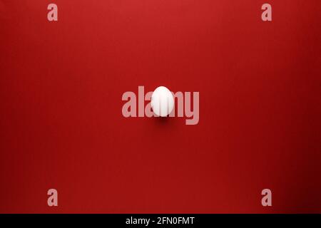 White easter egg with happy easter word, holiday concept. Red background. Top view Stock Photo