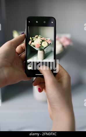 girl blogger takes a photo of flowers on her phone Stock Photo