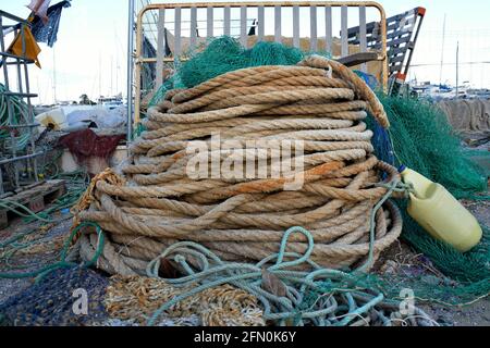 A coil of rope and some fishing nets and other equipment lying on the docks Stock Photo