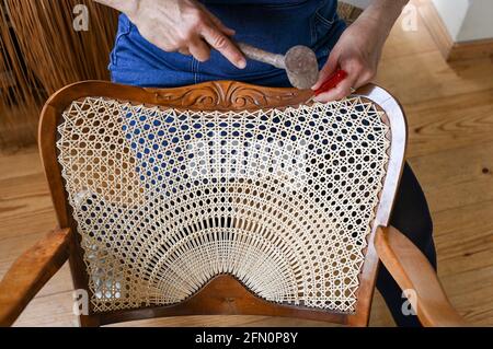 Berlin Germany. 12th May 2021. Chair weaver Silke Schlittermann works on repairing an armchair with half sun weave in her workshop in Kopenick. Chair weaving cane the bark of rattan is used